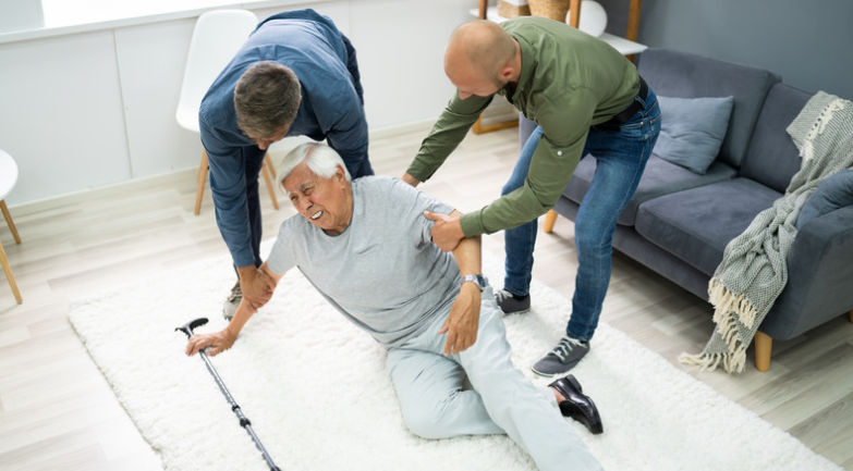 two men help senior who falls